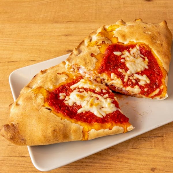 A golden-brown Romio's calzone, cut in half, revealing rich red sauce and melted mozzarella cheese.