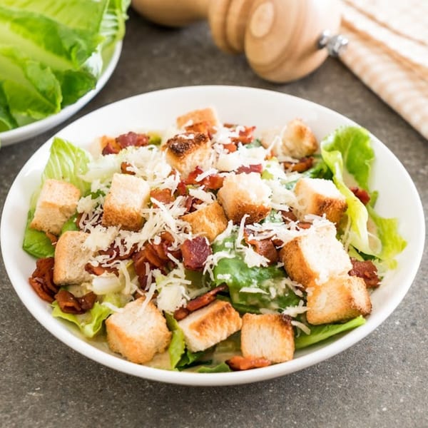 Romio's Caesar salad with crisp romaine, croutons, bacon bits, and shredded Parmesan cheese.