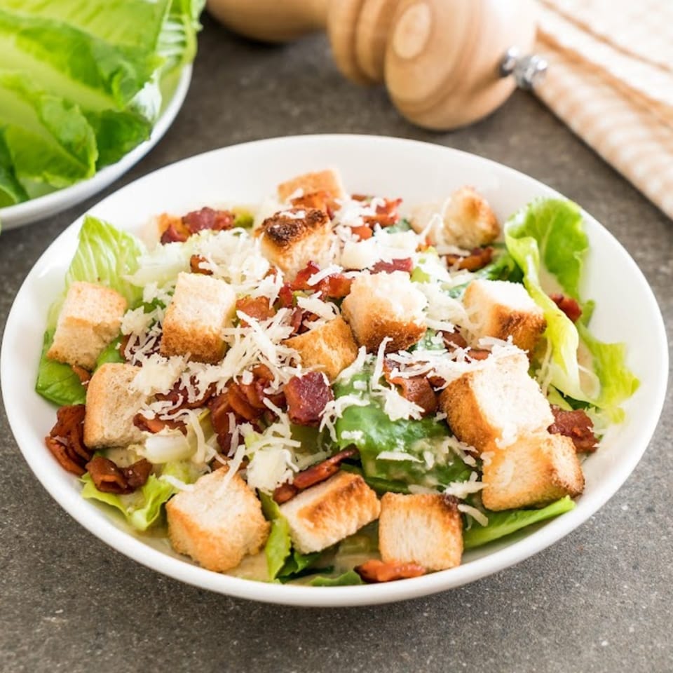Romio's Caesar salad with crisp romaine, croutons, bacon bits, and shredded Parmesan cheese.